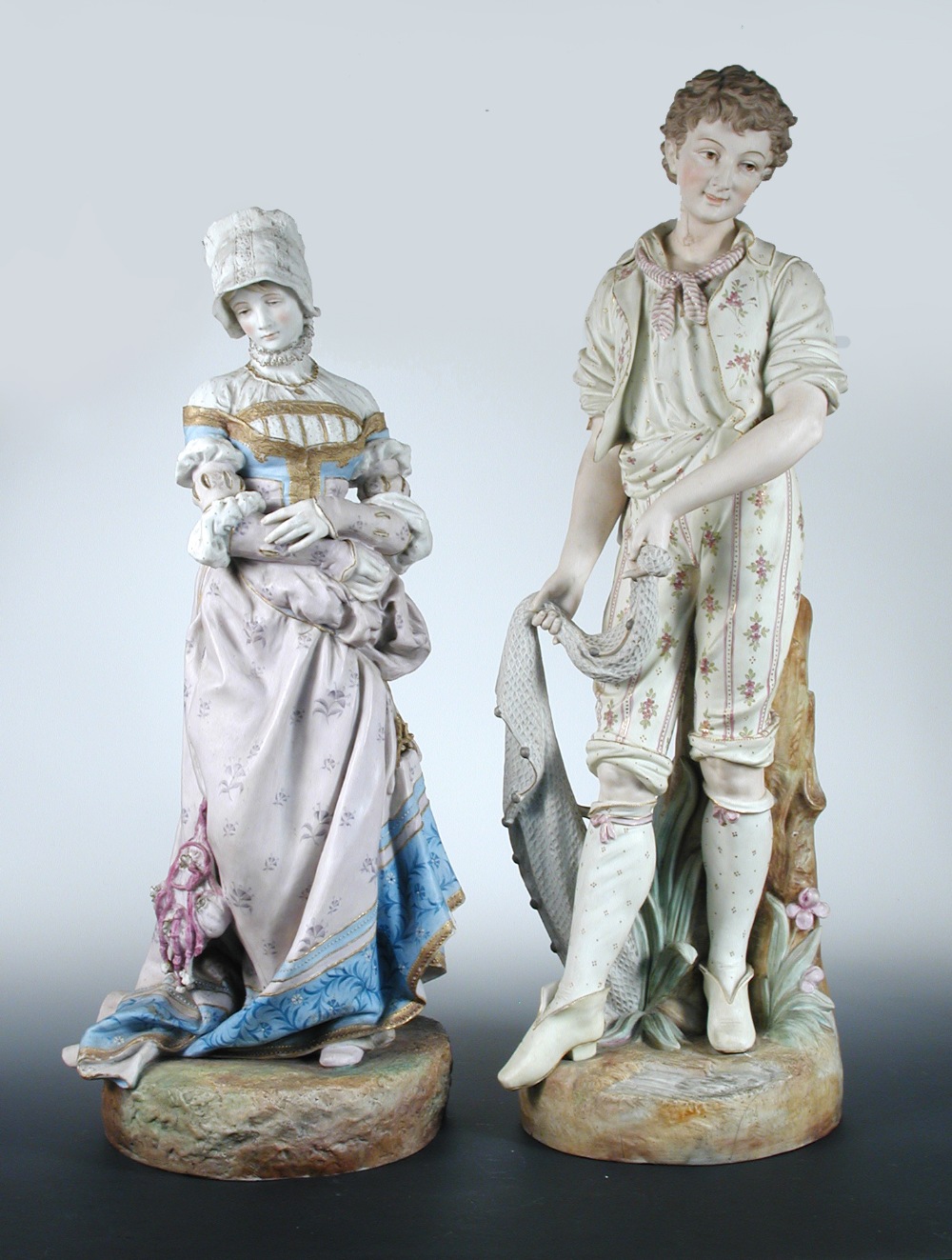 Two 19th century French bisque figures, the lady in Renaissance dress, the man holding a fishing