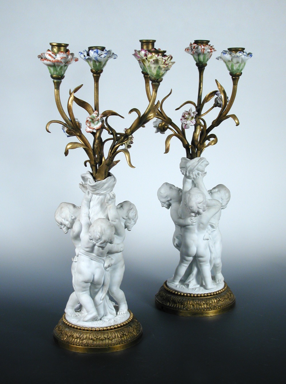 A pair of 19th century French biscuit three light candelabra, each with three children holding up