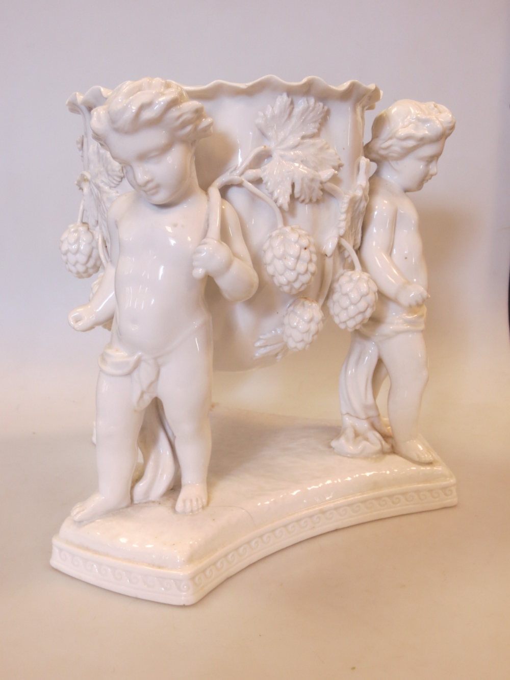 A Spode / Copeland china table vase of three cherubs holding a vine molded vase