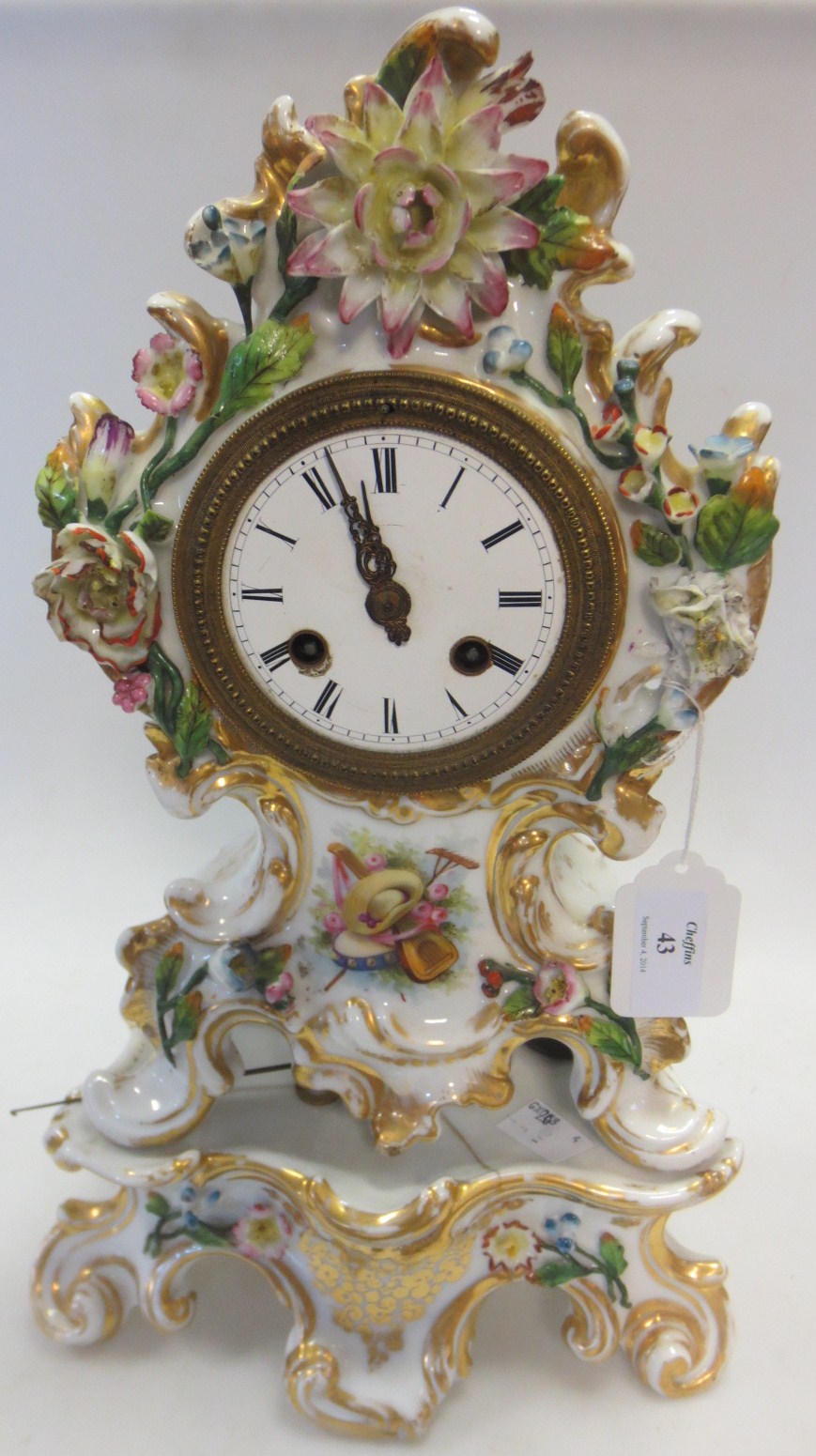 A 19th century floral encrusted porcelain timepiece and stand