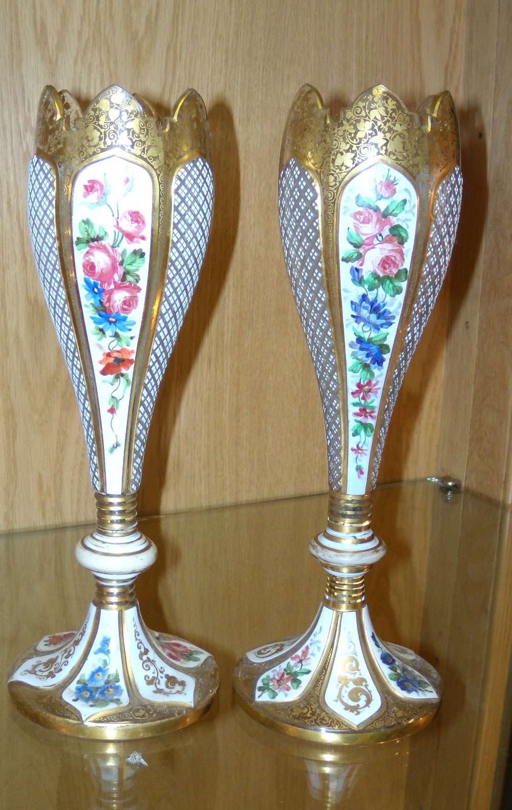 A pair of mid 19th century Bohemian vases, the gilt serrated rims to the tall tulip shaped bodies