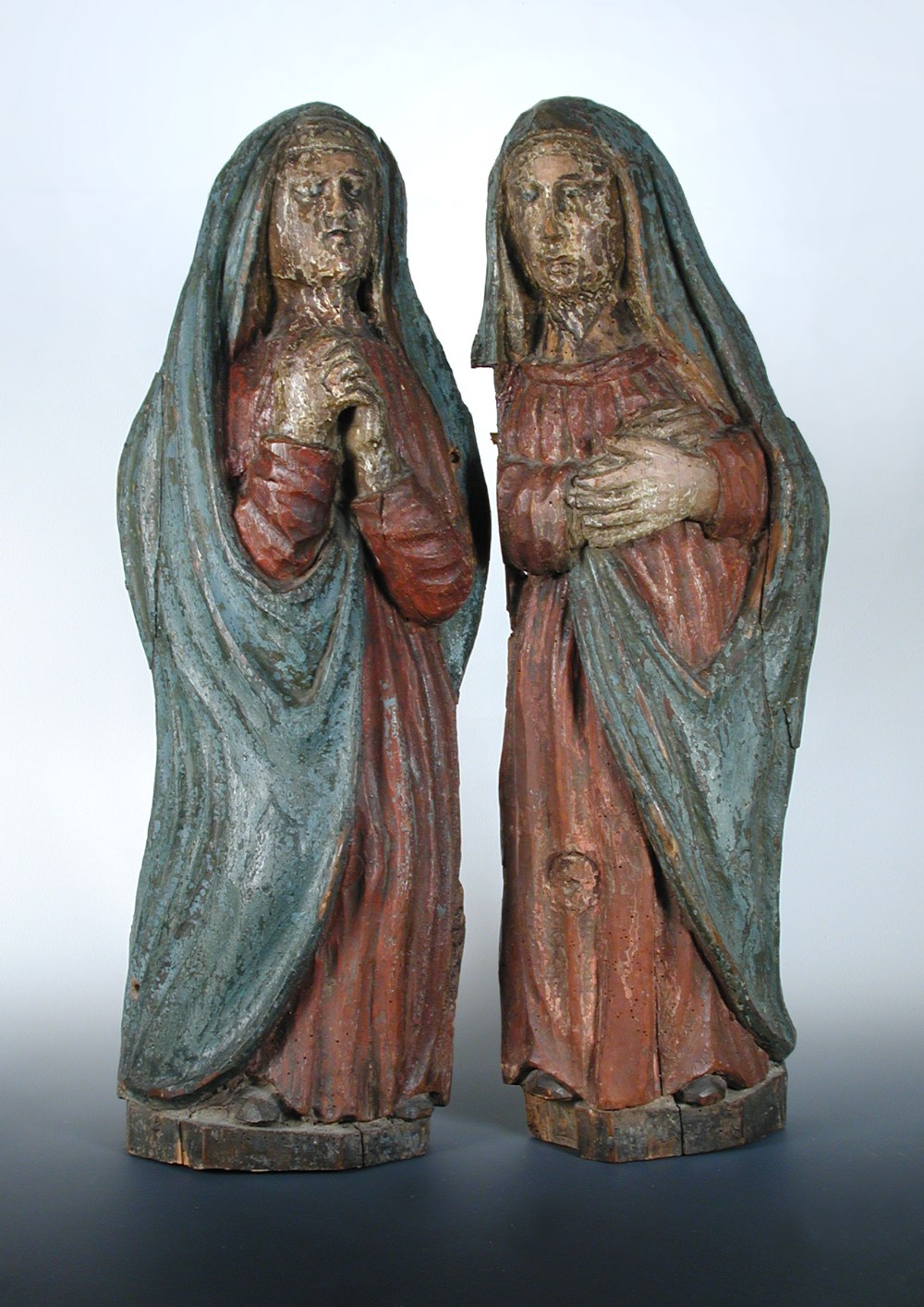 A pair of 16th century French polychromed pine figures of female saints wearing blue shawls over