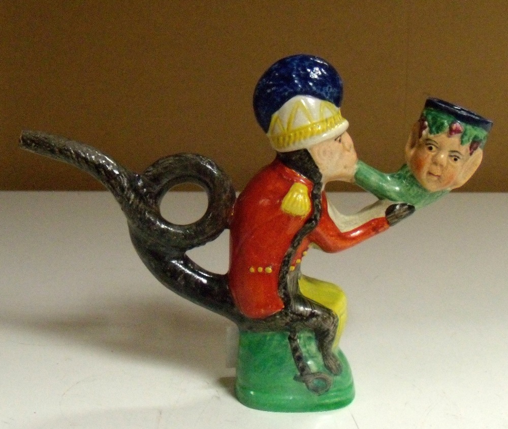 A19th century pearlware pipe modelled in the form of a monkey red coat soldier in turn smoking a