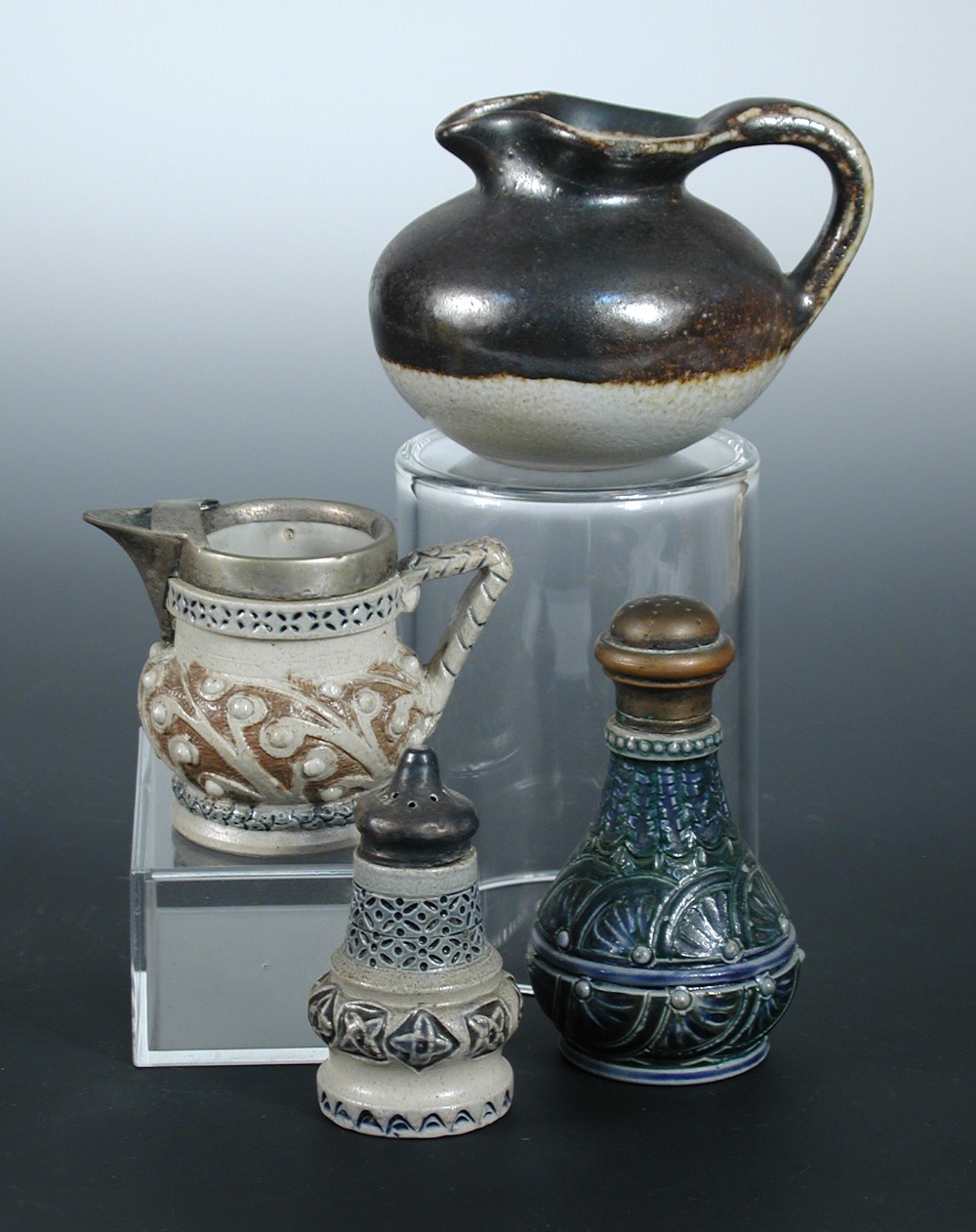 A collection of Martin Brothers miniature wares, comprising two jugs, a silver mounted pepper caster