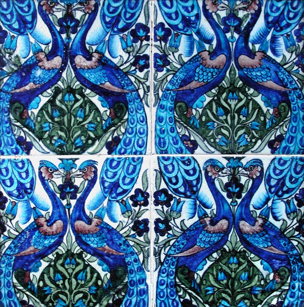 William De Morgan, a framed group of four tiles, painted with pairs of facing peacocks divided by