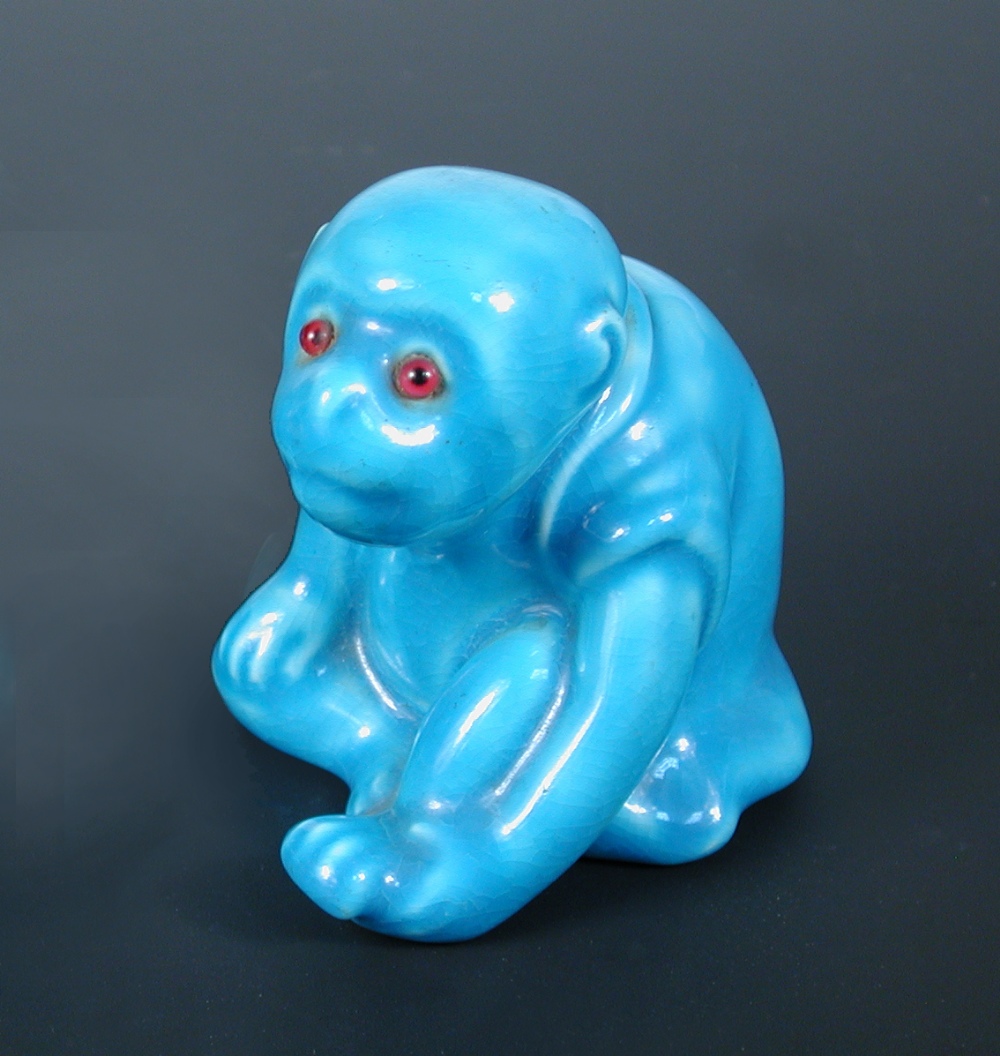 A Bernard Moore turquoise glazed monkey, modelled seated wearing a waistcoat, inset glass eyes,