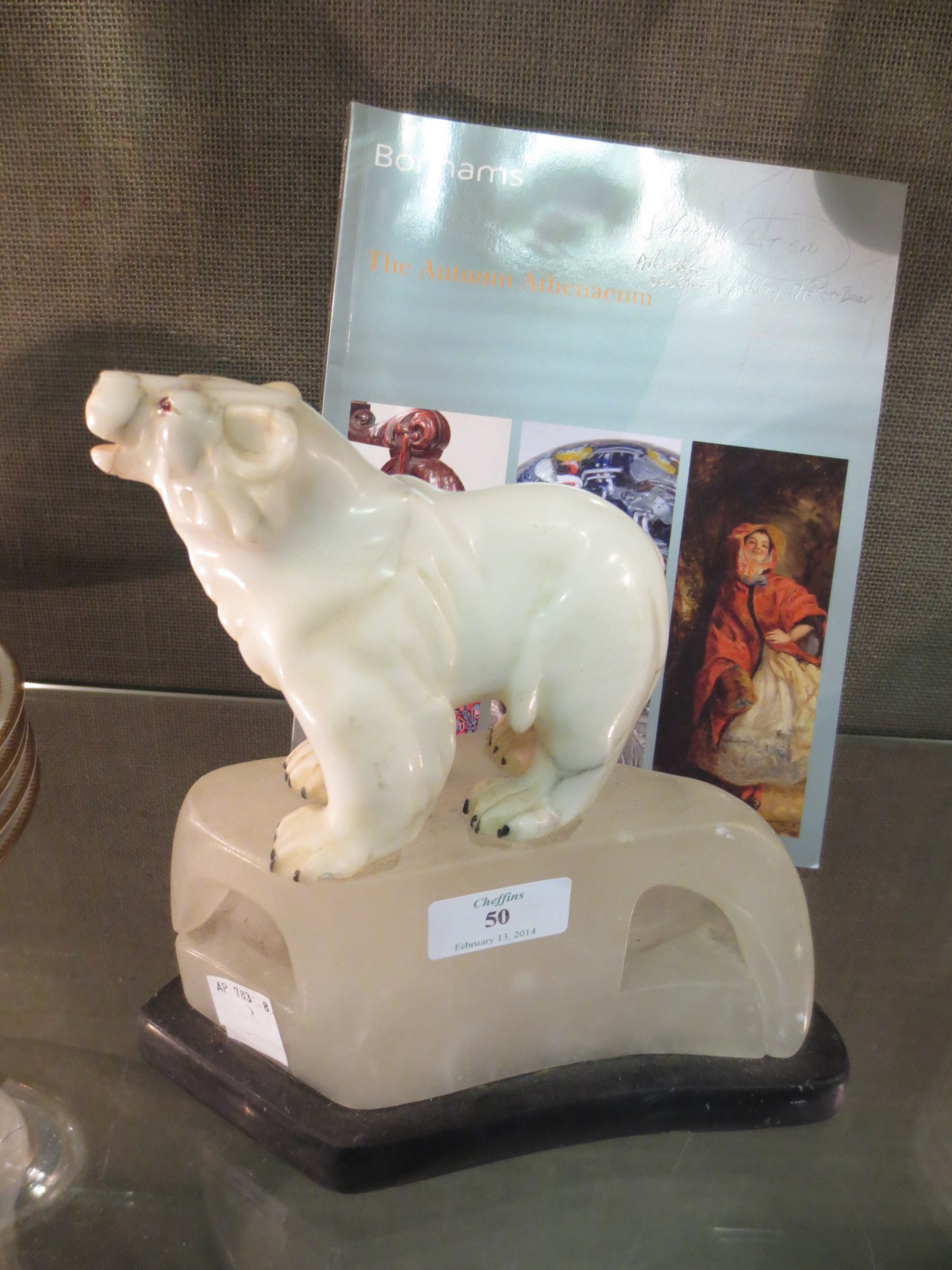 A carved marble polar bear together with the Bonham`s purchase catalogue
