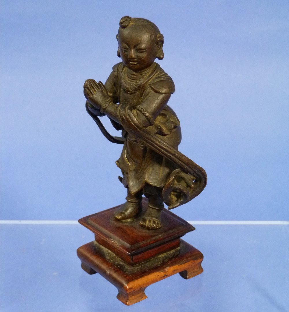 An antique oriental bronze figure, of a young man, modelled standing in flowing robes and with
