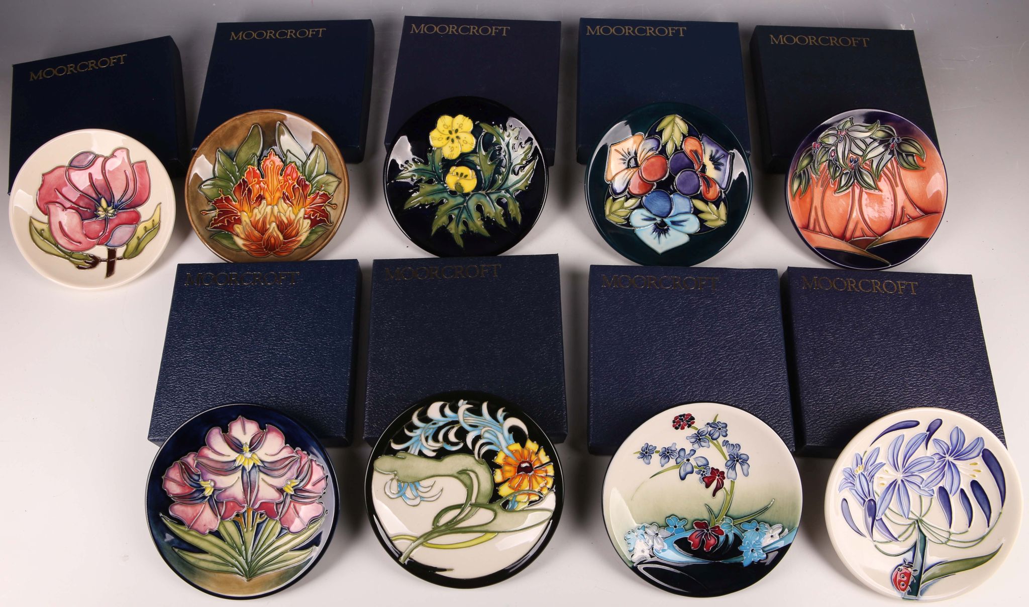 A collection of nine modern Moorcroft pottery circular shaped pin dishes, all tube-lined with