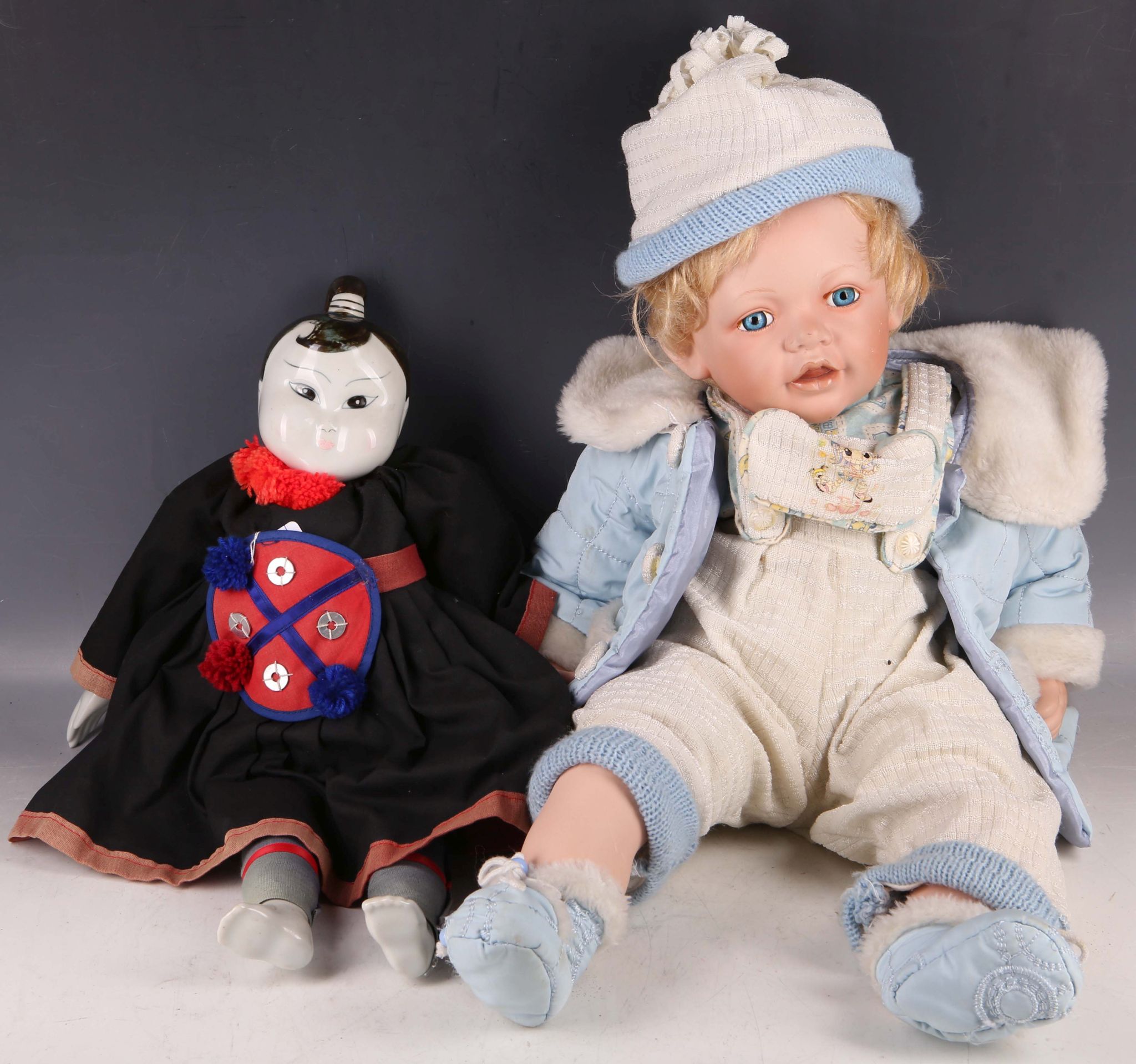 A Chinese porcelain headed doll in typical costume, sold together with a European doll in baby