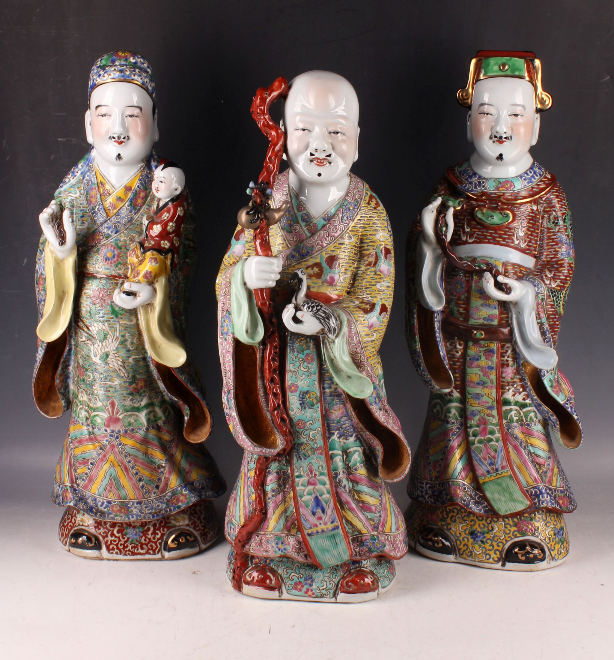 Three Chinese porcelain figures of officials in enamelled decorated robes, 50cm H. (3)