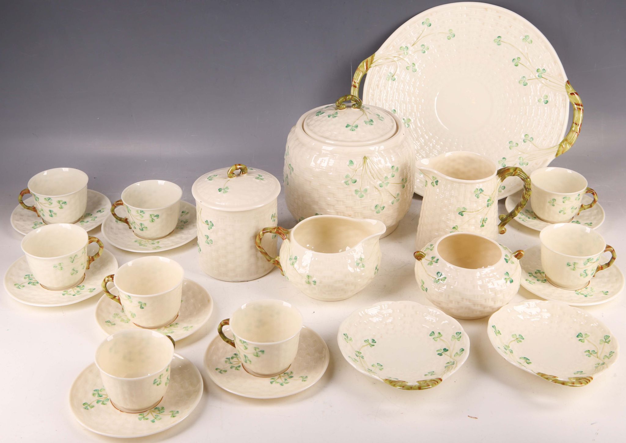 An Irish Belleek sixth period shamrock pattern teaware; eight cups and saucers, cake plate, butter /
