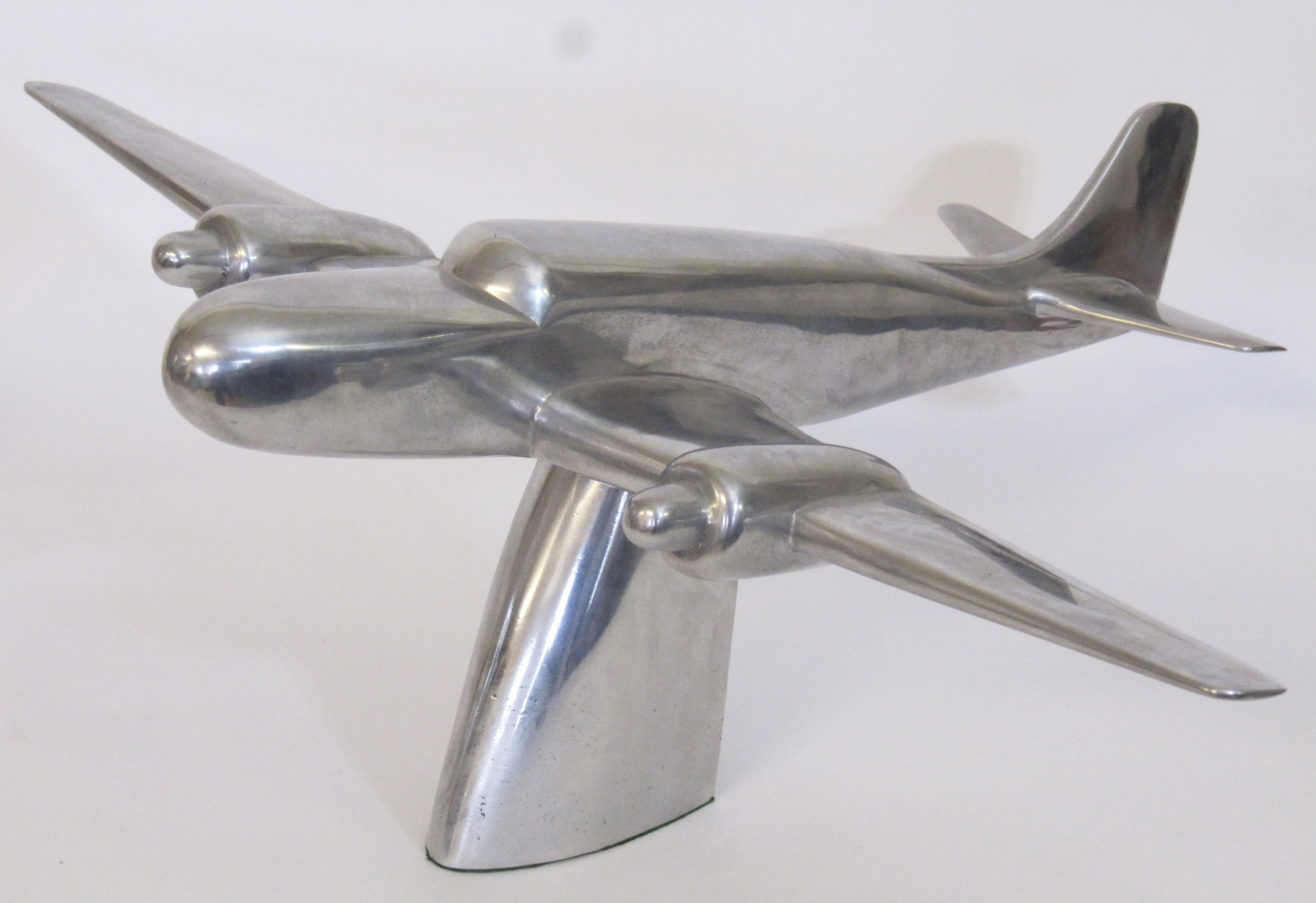 A polished steel model of a propeller aeroplane, mid 20th Century, raised upon a pedestal base, 80cm