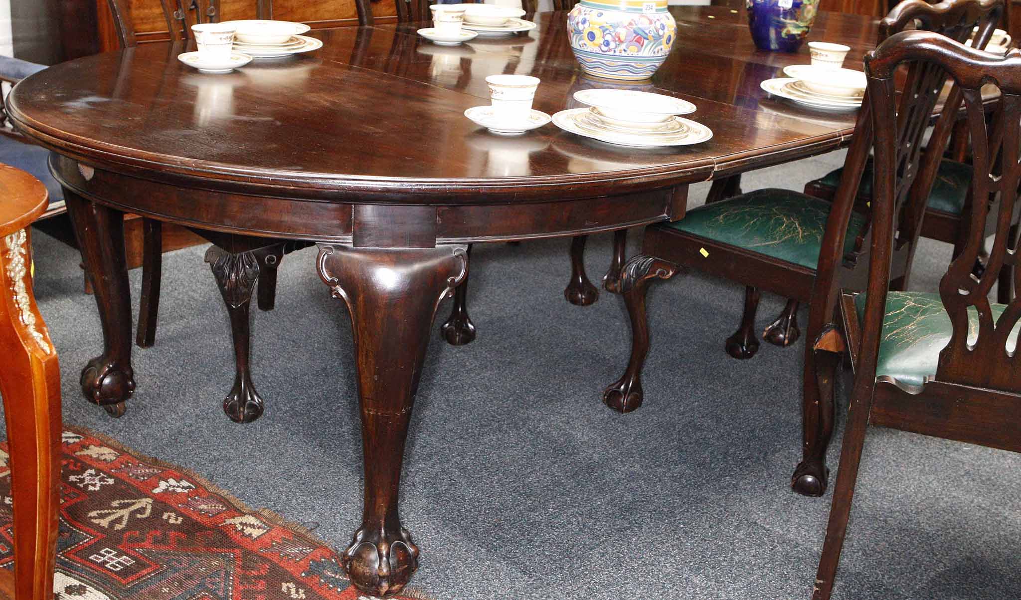 A 1930 walnut extending dining table, raised on cabriole legs on claw and ball feet, with three