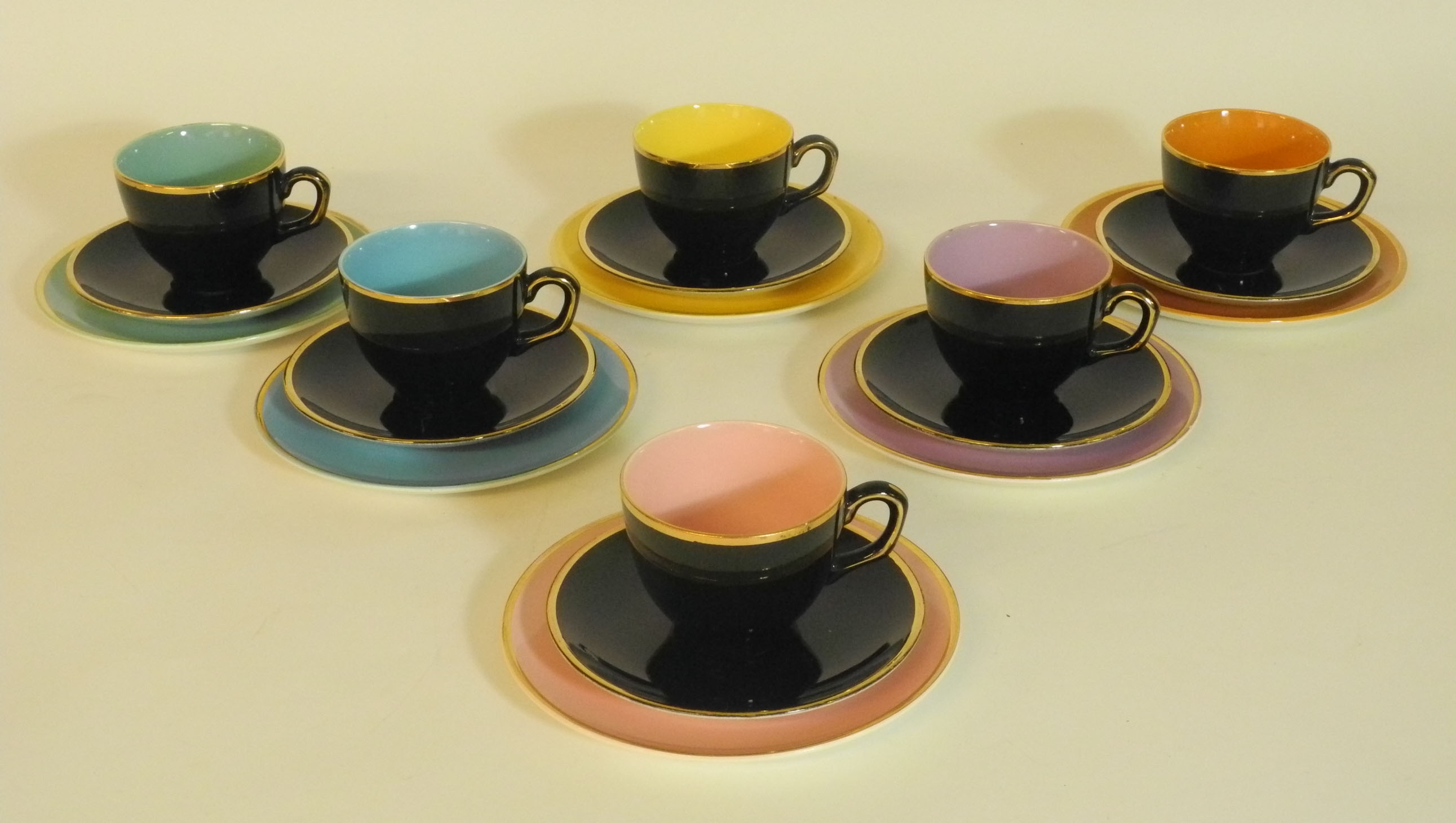 A set of six Palissy `Madeline` tea cups and saucers, with black glaze exterior heightened with 22