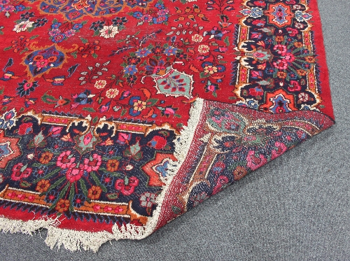 A Hamadan carpet with starburst central floral medallion on a crimson ground floral field within a - Image 2 of 3