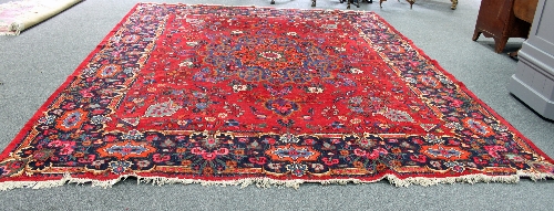 A Hamadan carpet with starburst central floral medallion on a crimson ground floral field within a