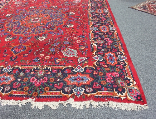 A Hamadan carpet with starburst central floral medallion on a crimson ground floral field within a - Image 3 of 3