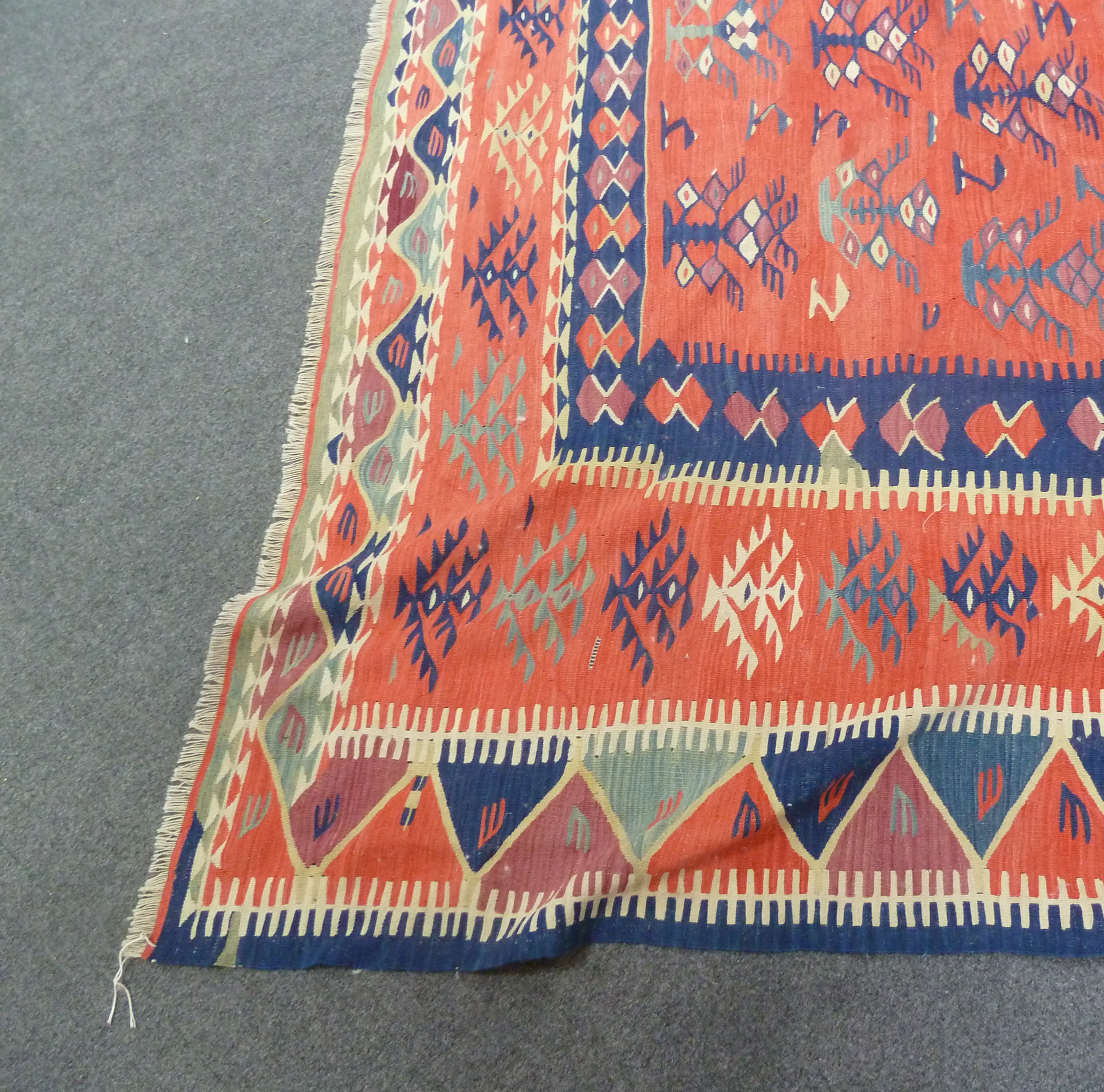 A Kelim rug with bright geometric designs on a tomato red ground, approximately 335cm (132") long