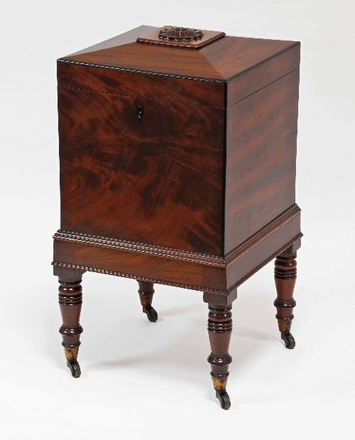A Regency mahogany bottle box of square form, the raised lid with carved flowerhead finial on turned