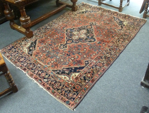 An Eastern rug, central indigo and white medallion on a madder ground, within guard stripe, 210cm