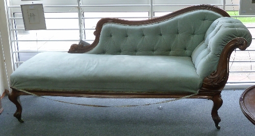 A Victorian carved walnut framed chaise longue, with scroll end on cabriole legs and castors