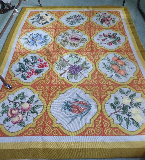 A needlework rug, of three rows of four quatrefoil panels, each with fruit motif,  207cm x 165cm (