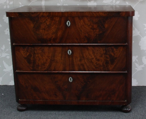 A Biedermeier chest of three long drawers with mother-of-pearl escutcheons and set on bun feet,