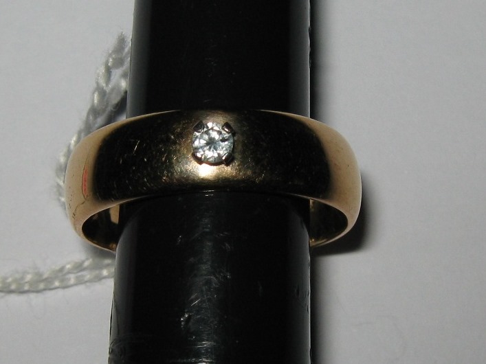 A gold band inset with a single diamond, unmarked but tested as 9ct