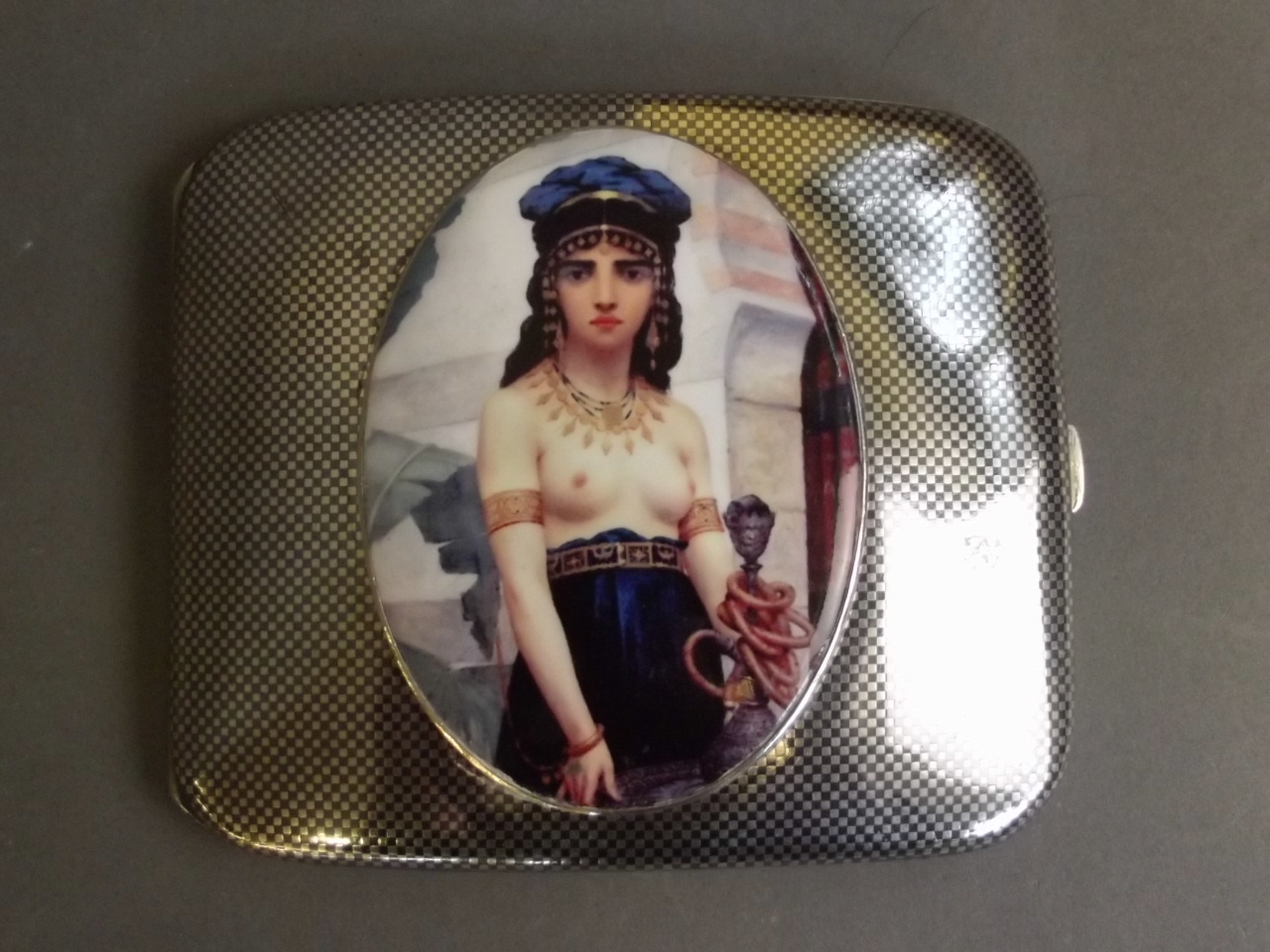 A Niello silver cigarette case with a later applied oval enamel plaque depicting a semi-naked