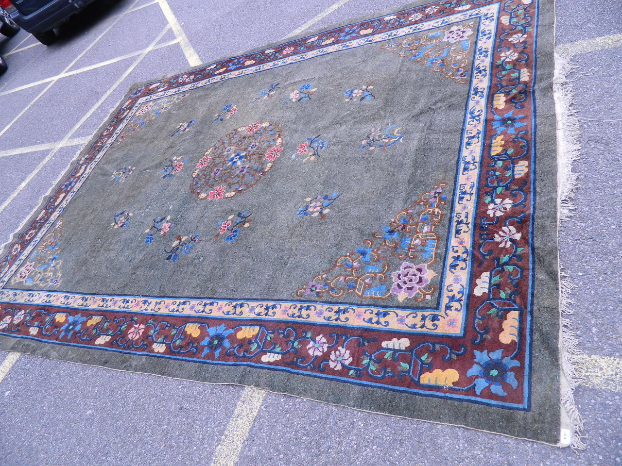 An antique Chinese carpet decorated with flowers on a jade green field, 144" x 109"