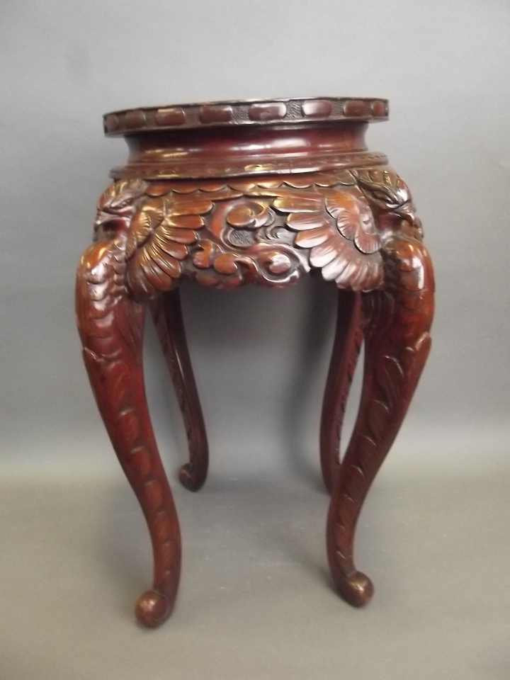 A C19th oriental carved wood stand with phoenix carved supports, 18" diameter, 24" high