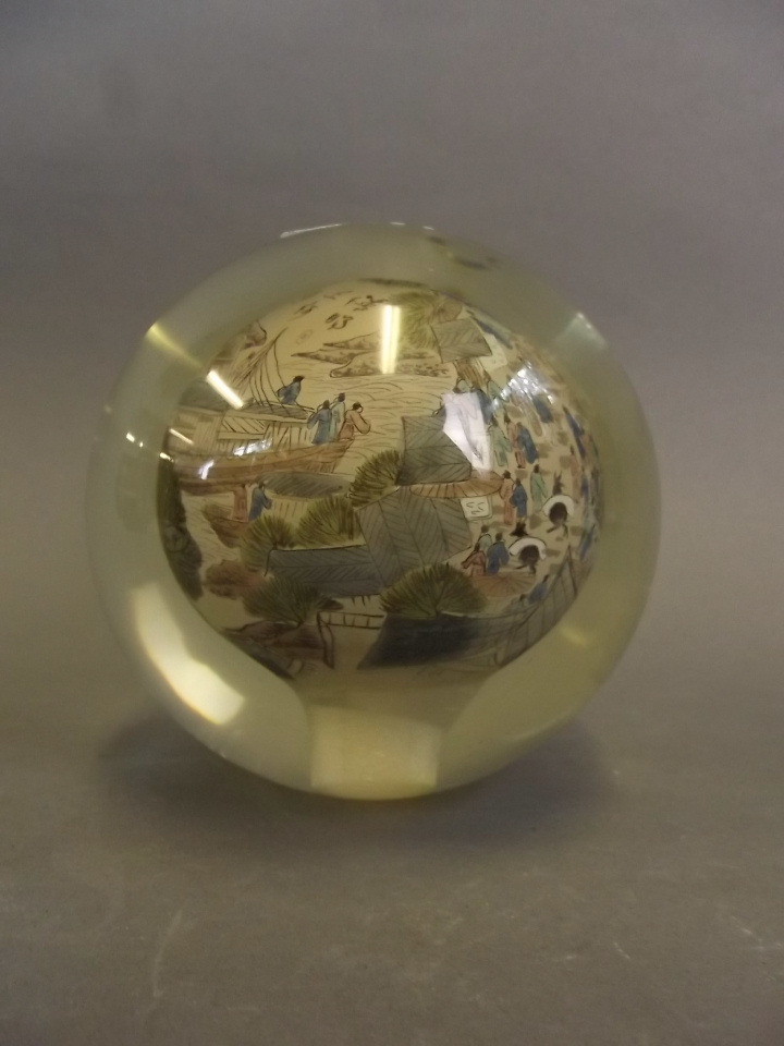 A large Chinese glass paperweight with interior painted decoration depicting figures and ships,