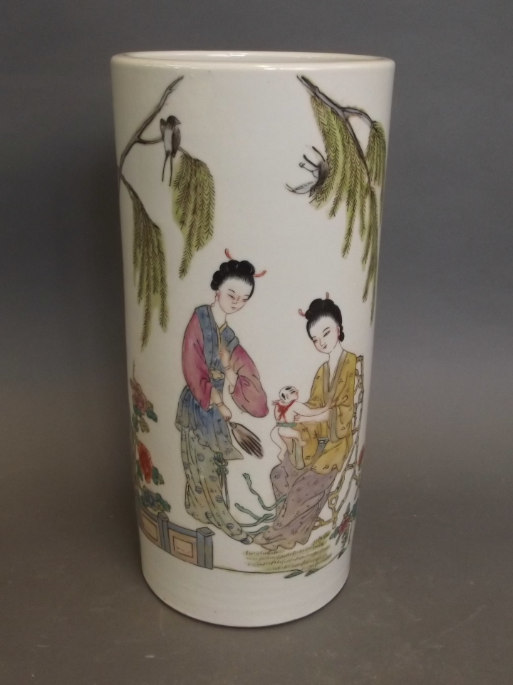 A Chinese porcelain cylindrical vase with painted enamel decoration of two women and a baby in an