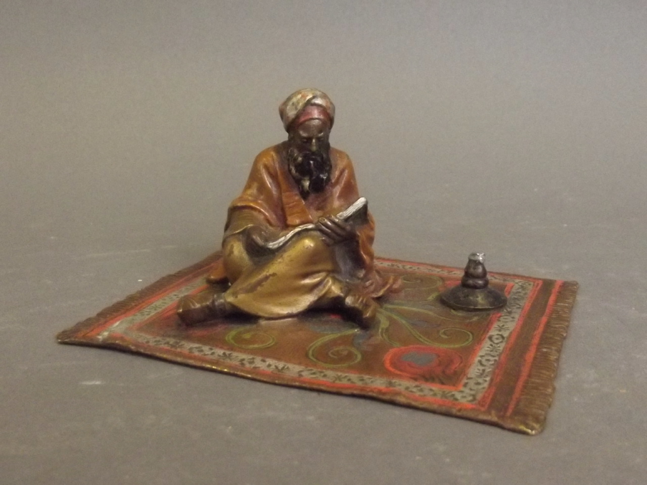 A cold painted bronze figure of an Arab scholar seated on a rug, 4¼" x 3¼"