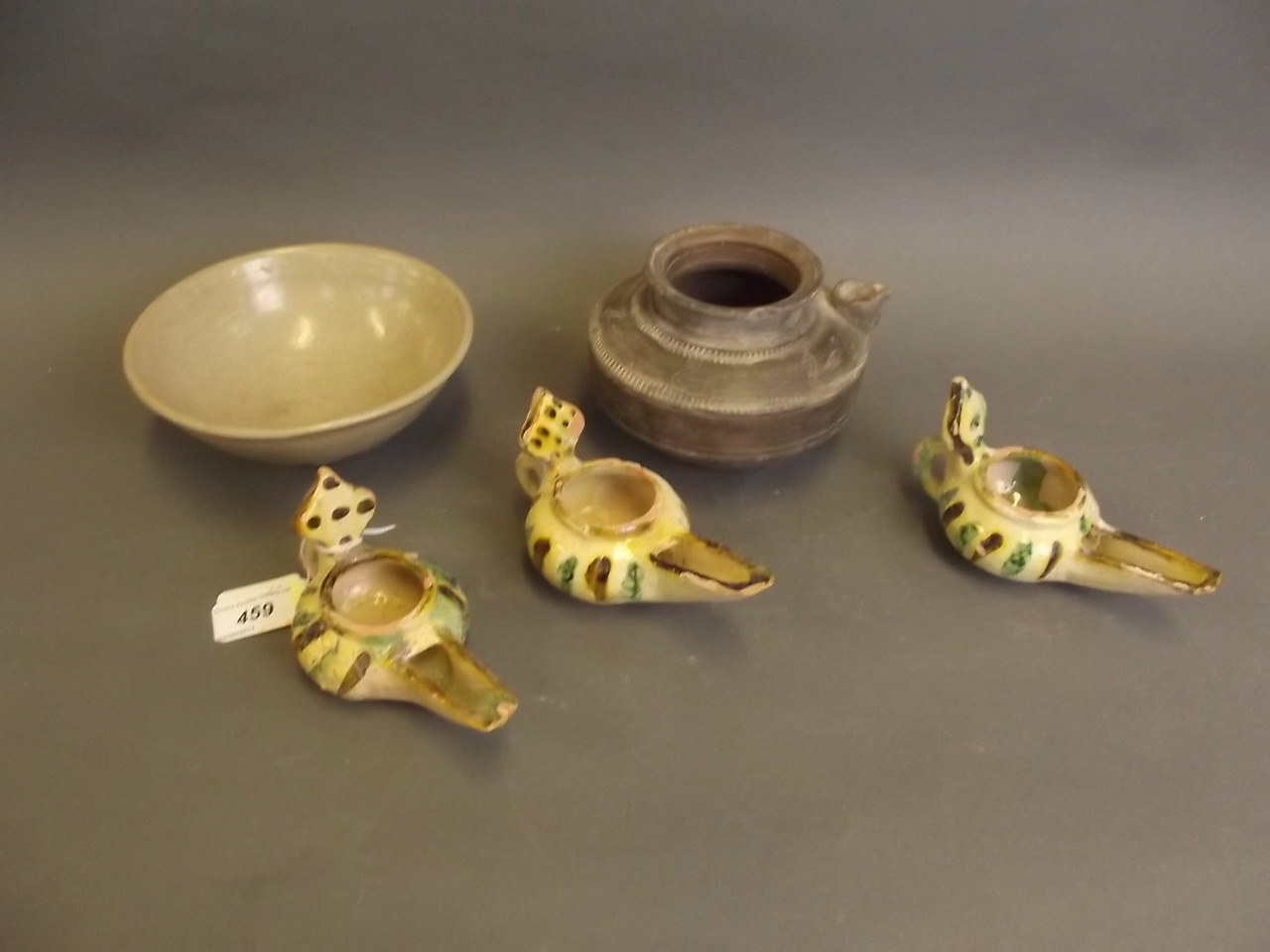 Three Islamic pottery oil lamps, 5½" wide, an Islamic pottery pourer and an Eastern pottery bowl