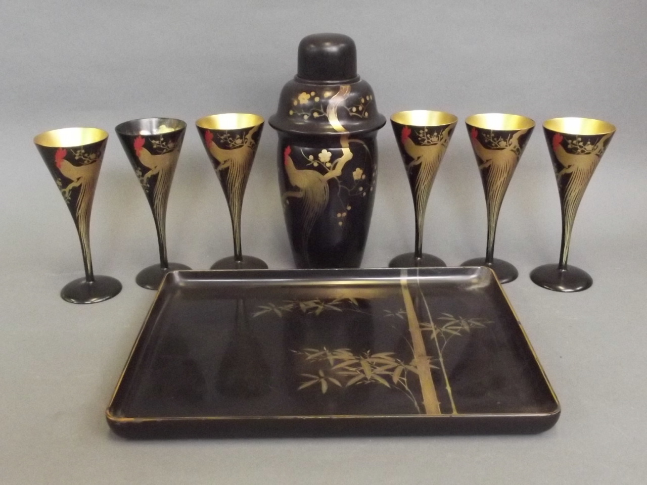 A Japanese black lacquer cocktail set to include a lacquer cocktail shaker, four lacquer goblets and