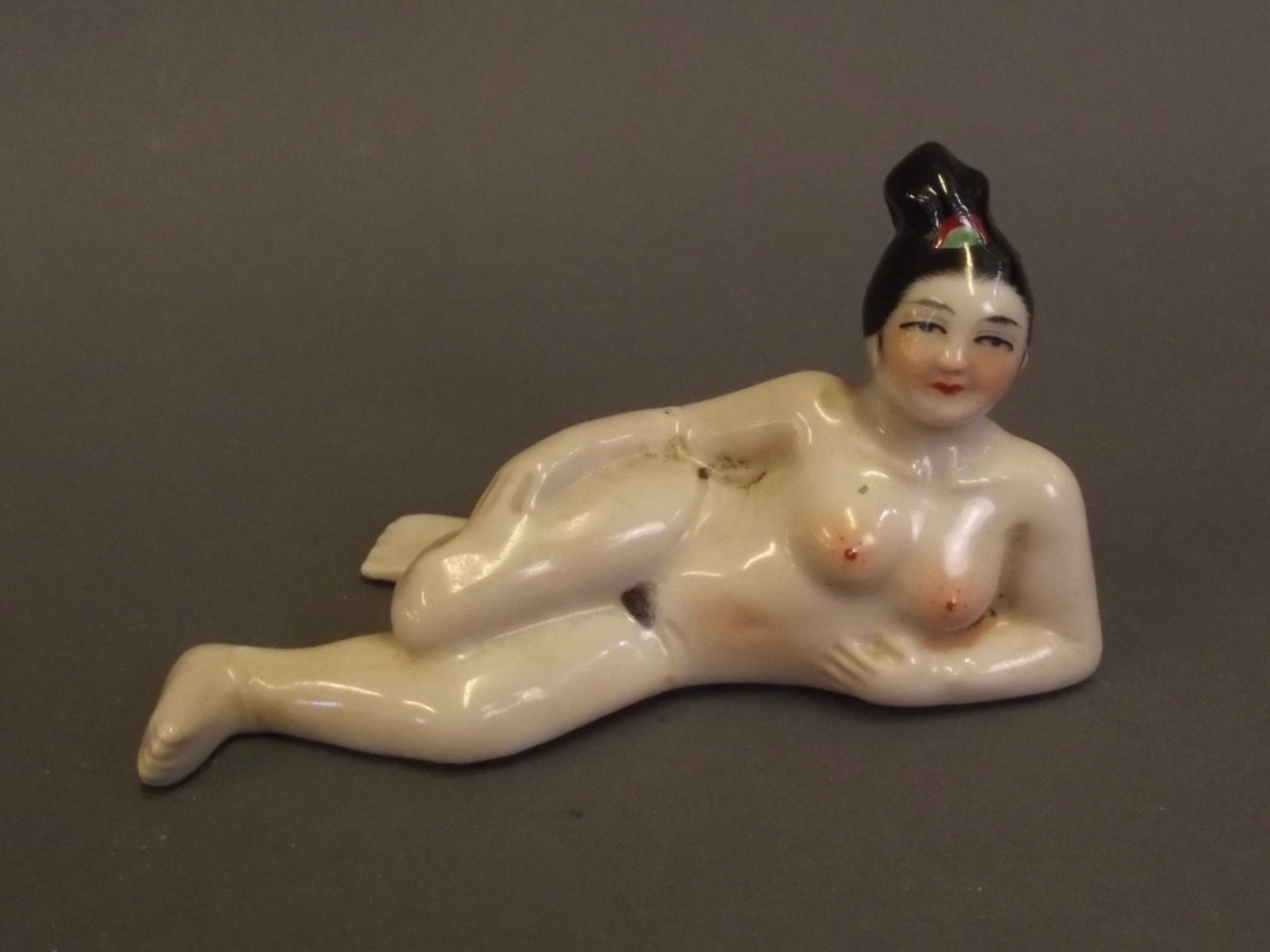 A Chinese porcelain scent bottle in the form of a reclining nude lady, 4¾'' long (without lid)