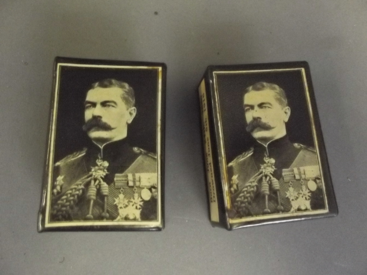 A pair of early C20th enamel matchbox holders in memoriam of Lord Kitchener, 2¼'' x 1½''