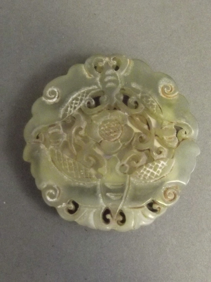 A Chinese pierced celadon jade pendant with carved butterfly and floral decoration, 1¾'' diameter