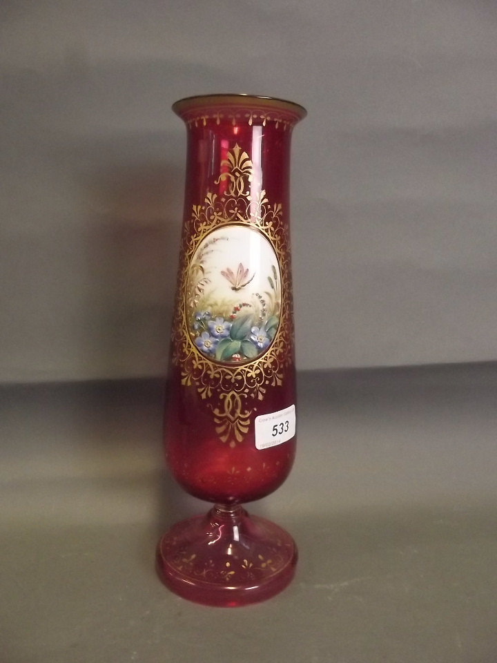 A C19th Bohemian ruby glass vase with a painted raised panel within a gilded border, 12¼'' high