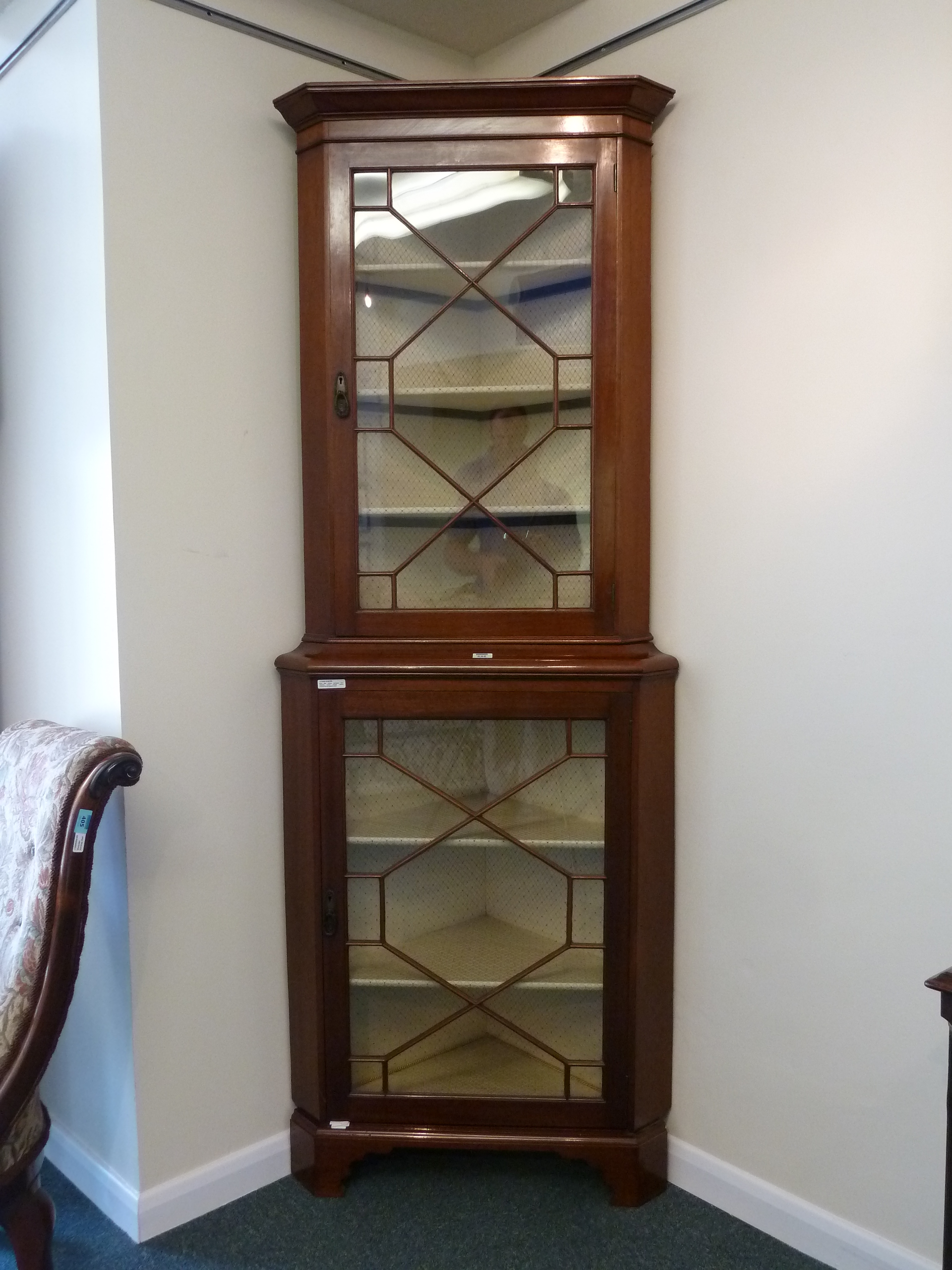 Early 20th century mahogany floor standing corner display cabinet enclosed by two glazed doors,