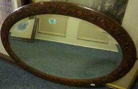 Edwardian oval bevelled edge wall mirror in carved oak frame