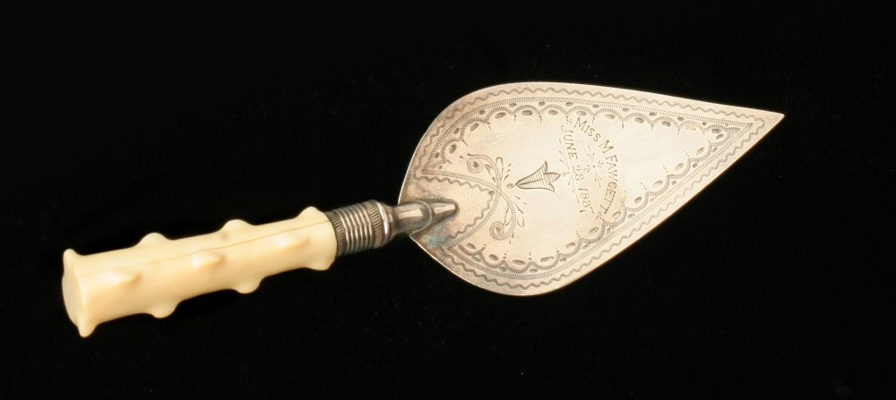 A small silver plated presentation trowel with Miss M Fawsett June 28 1887 with decorative surround,