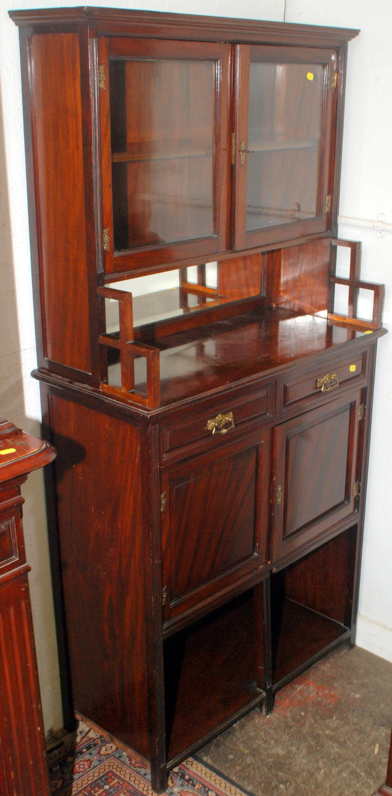 A late Victorian mahogany small cabinet in the manner of E.W. Godwin, the upper section with two