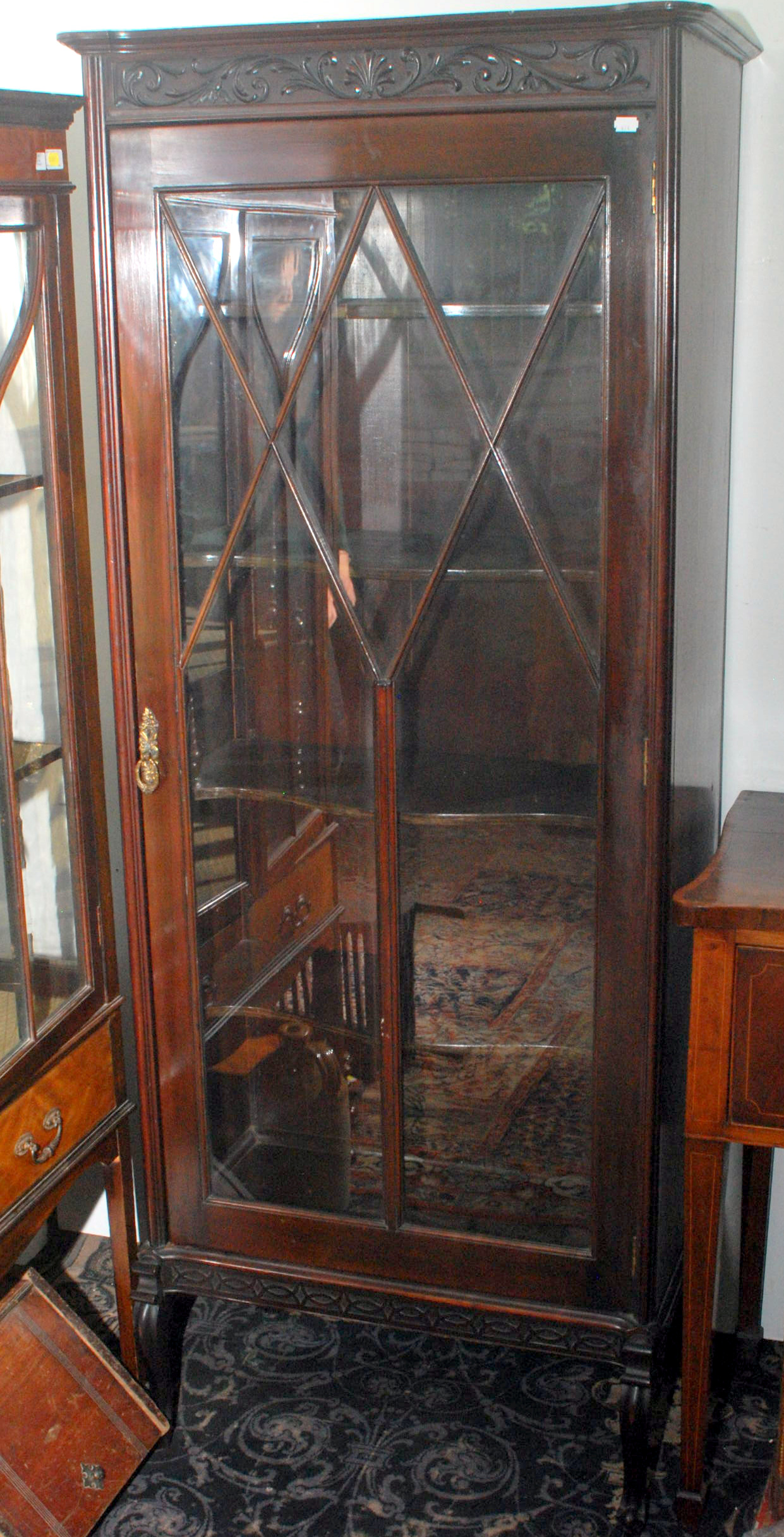 A late Victorian mahogany display cabinet with carved decoration and serpentine shelves on