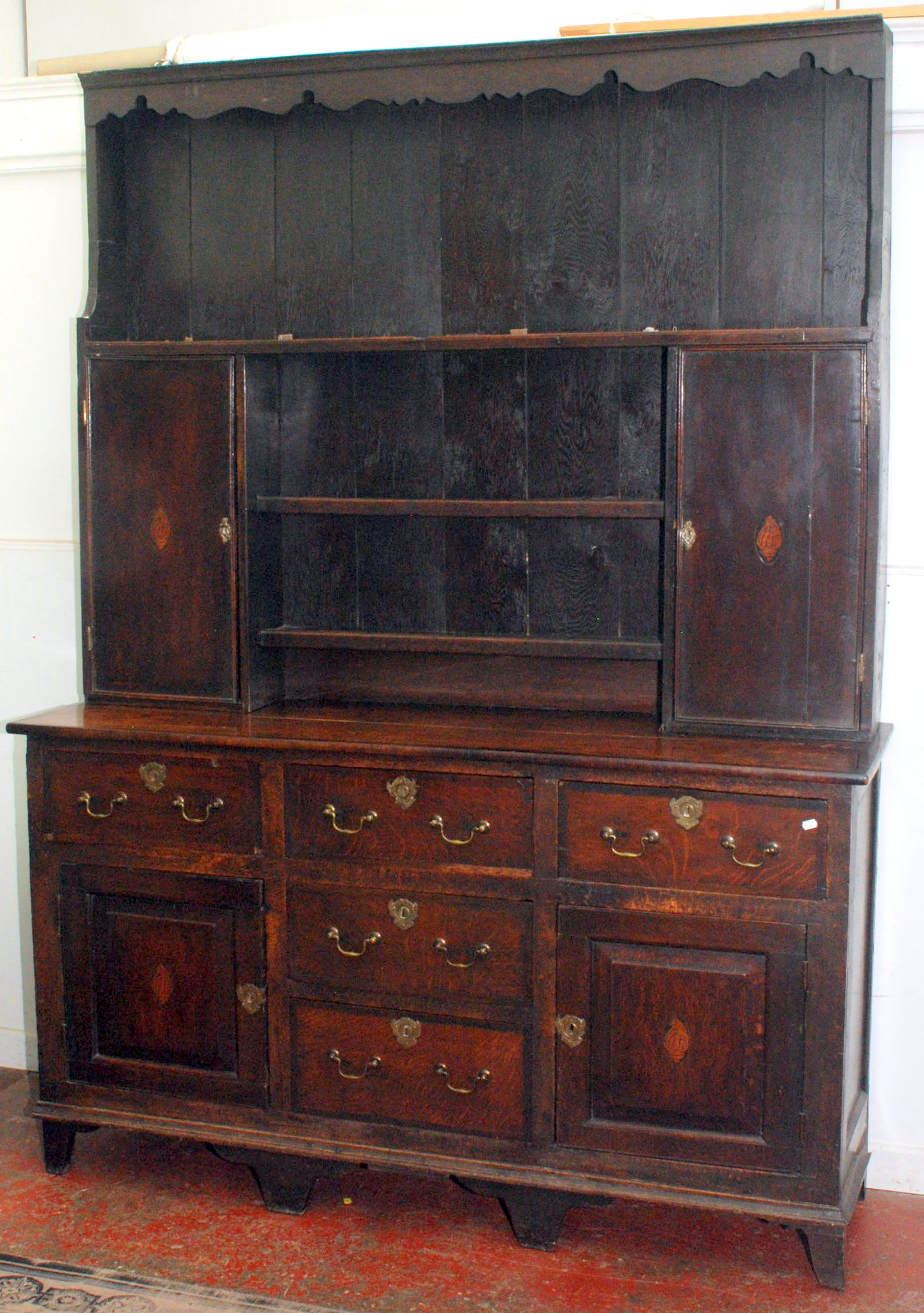An oak 18th century dresser with cross-banding and inlaid shell motif, the upper section with open