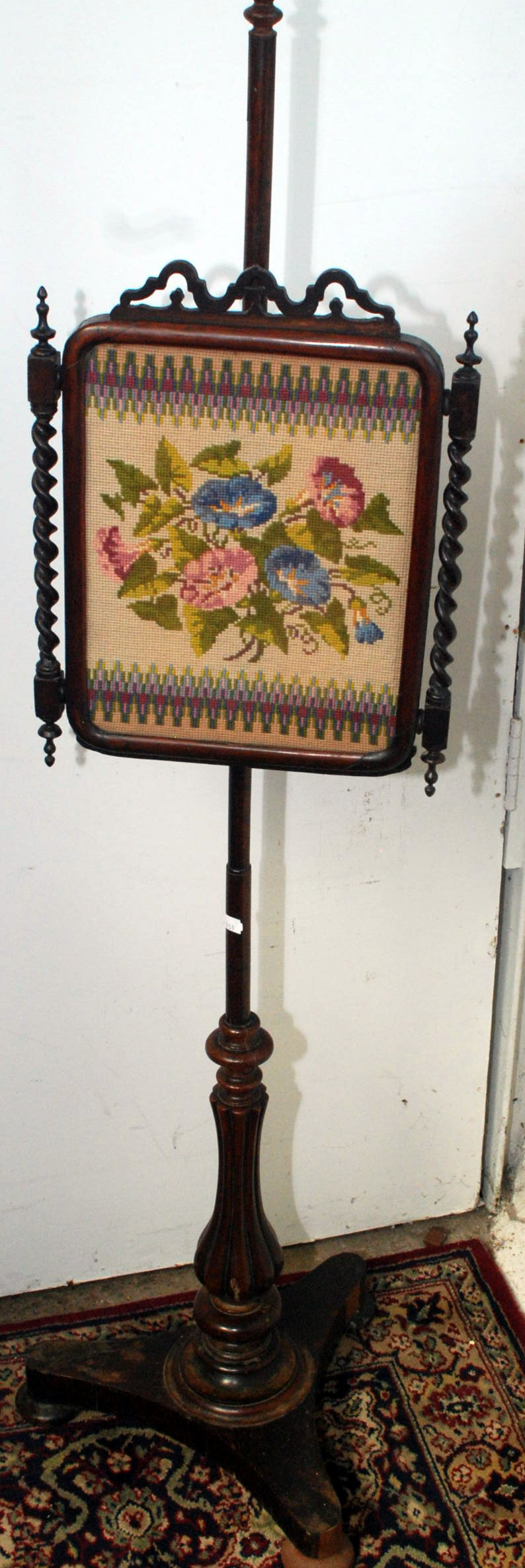 A Victorian pole screen with needlework panel.