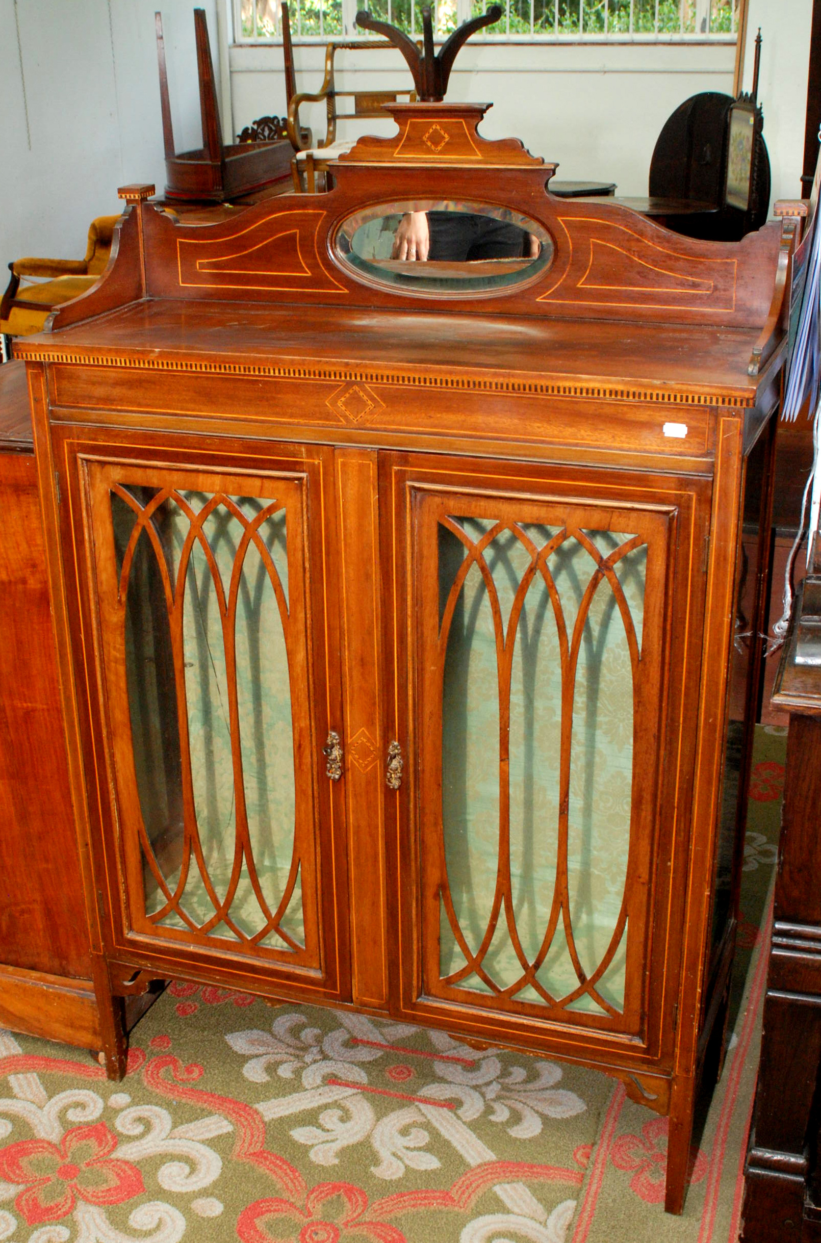 An Edwardian inlaid mahogany display cabinet, the low back set a mirror.