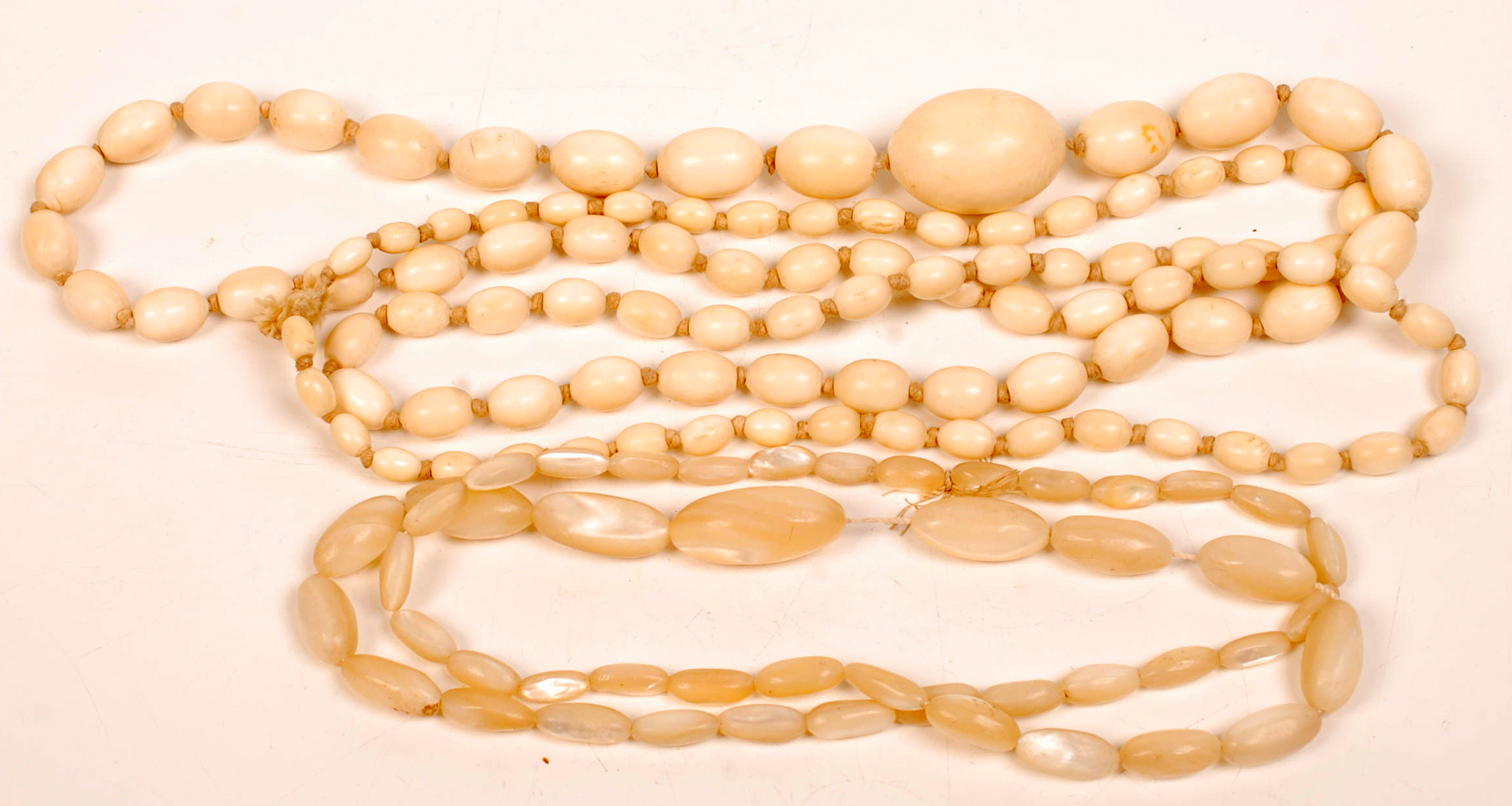 A long graduated ivory oval bead necklace and a similar mother of pearl necklace. Condition